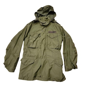 May include: An olive green military jacket with a hood and multiple pockets. The jacket has the text "U.S. ARMY" on a patch above the chest pocket. The jacket has a button and zipper closure.
