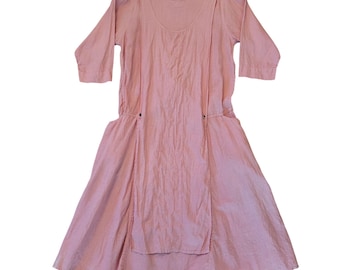 May include: A light pink dress with a scoop neckline and three-quarter sleeves. The dress features a gathered waist and a flared skirt. The fabric appears to be a lightweight linen or cotton blend. The dress has a relaxed, comfortable style.
