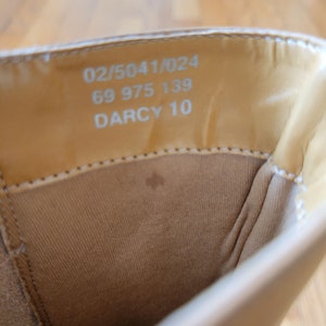 May include: Close-up of the inside of a light brown shoe with the text "02/5041/024 69 975 139 DARCY 10" printed on the insole.