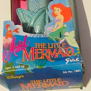 May include: A vintage Ariel The Little Mermaid doll in a blue and green mermaid tail, packaged in a blue and pink box with the text "Ariel The Little Mermaid" and "Disney's The Little Mermaid".