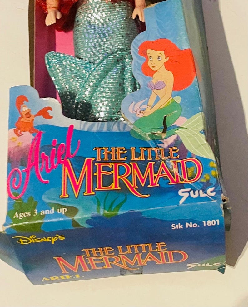 May include: A vintage Ariel The Little Mermaid doll in a blue and green mermaid tail, packaged in a blue and pink box with the text "Ariel The Little Mermaid" and "Disney's The Little Mermaid".