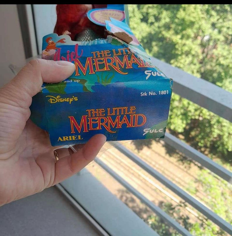May include: A blue and white box with the text "Disney's The Little Mermaid" and "Ariel" on it. The box has a picture of Ariel, a mermaid, on it. The box is for a toy.