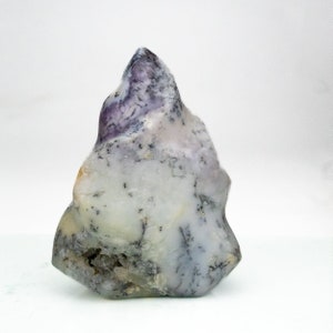May include: A natural, uncut stone with a light gray and white base, accented with purple and black veining. The stone has a rough, irregular shape and a smooth, polished surface. The overall form is reminiscent of a small mountain or peak.