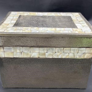 May include: A silver box with a textured surface and a decorative top made of white mother-of-pearl tiles.