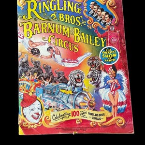 May include: A vintage Ringling Bros. and Barnum & Bailey Circus souvenir program featuring colorful illustrations of acrobats, elephants, tigers, a clown, and a train. The cover text reads Celebrating 100 Years of Ringling Bros. Circus.