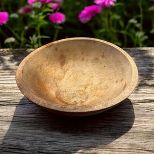 May include: A wooden bowl with a natural wood finish. The bowl is empty and has a smooth, rounded surface.