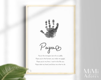 Puede incluir: Una huella de mano en blanco y negro con la palabra "Papa" escrita en cursiva con un corazón al lado. El texto debajo dice "You're the strongest, but oh so cuddly. Papa you're the funnest, you make me giggly. Papa you're my hero, I want to be like you. Papa take my hand, and show me what to do."