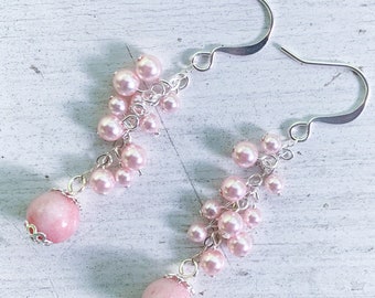 May include: A pair of drop earrings featuring silver-toned hooks and a cluster of small, round, light pink faux pearls. Each earring terminates in a larger, smooth, opaque pink stone bead accented with a decorative silver-toned metal bead cap.