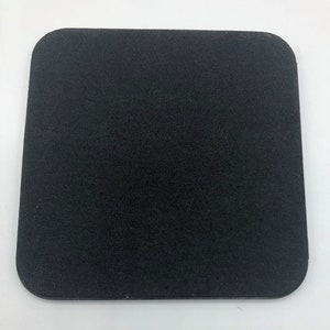 May include: A black square-shaped coaster made of a textured material.