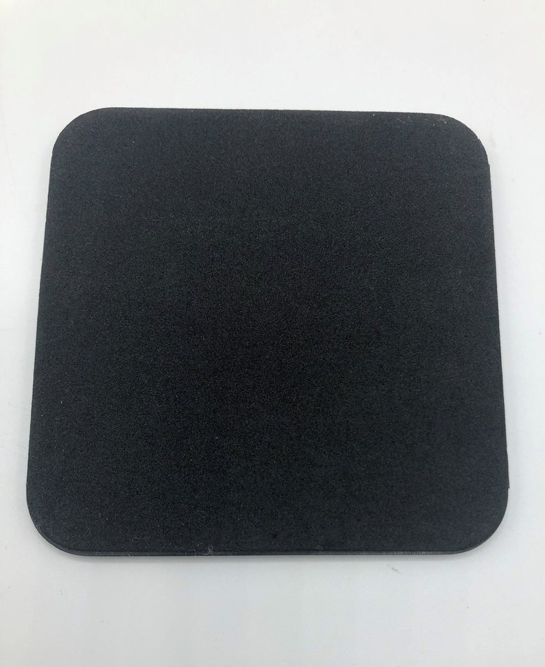 May include: A black square-shaped coaster made of a textured material.