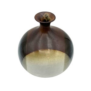 May include: A round ceramic vase with a brown, tan, and white glaze. The vase has a wide mouth and a narrow neck.