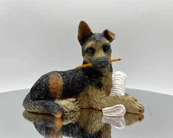 German Shepherd Cast Figurine, Paper under paw and holding pencil in mouth.  Very Highly Detailed.  3.75" long x 2.5" high