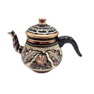 May include: A traditional Turkish copper teapot with a black and white floral design. The teapot has a copper lid and a black handle.