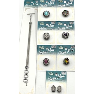May include: A silver-toned bracelet with a T-bar clasp and several charm beads. Several charm beads are displayed on cards, including a turquoise bead, a floral bead, a heart-shaped bead, and others.