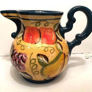 Young's Exclusive 1999 Pitcher - Pottery with beautiful handpainted artwork of fruit and vines.  8" from spout to handle and 6" high.