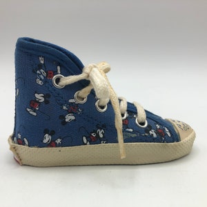May include: Blue canvas high-top trainers with a white sole and white laces. The trainers are covered in a pattern of Mickey Mouse characters.