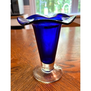 May include: A cobalt blue glass vase with a flared, ruffled opening and a clear glass base.