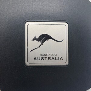 May include: A silver metal plaque with a black silhouette of a kangaroo jumping. The plaque has the words "Kangaroo Australia" printed on it.