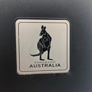 May include: A silver metal sign with a black silhouette of a kangaroo and the text "Kangaroo Australia".