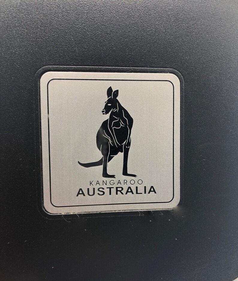May include: A silver metal sign with a black silhouette of a kangaroo and the text "Kangaroo Australia".