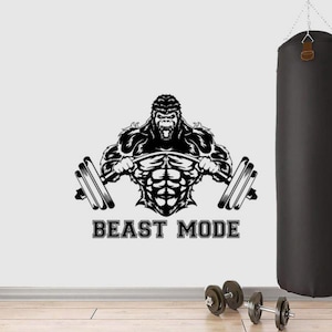 May include: Black and white graphic of a gorilla lifting a barbell, with the text "BEAST MODE" below. A black punching bag hangs in the background, with dumbbells on the floor. The image is a motivational fitness design.