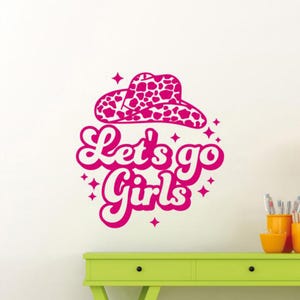 May include: Pink and white wall decal with the text "Let's go girls" and a pink and white cowboy hat.