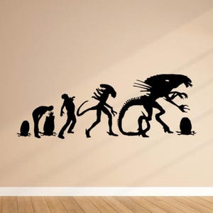 May include: Black and white silhouette wall decal of the evolution of the Alien creature from the movie franchise. The decal shows the creature's progression from an egg to its final form.