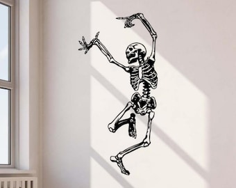 May include: Black and white skeleton wall sticker in a dancing pose. The skeletal figure has its arms raised, with one hand pointing upwards and the other outstretched. The sticker is applied to a white wall, creating a striking contrast.
