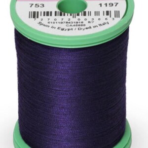 May include: A spool of Sulky brand thread, 100% cotton, in a deep purple color. The spool has a green base and top, with the text "THREAD by SULKY" and product information printed on the label.