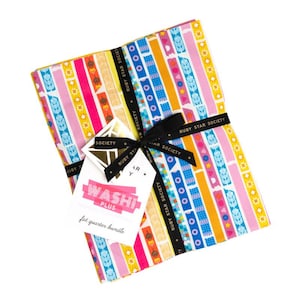 May include: A stack of colorful fabric fat quarters, patterned with vertical stripes in pink, blue, yellow, and orange. The bundle is tied with a black ribbon and a tag that reads "Washi Plus fat quarter bundle."
