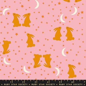 May include: Pink fabric with a repeating pattern of orange rabbits, stars, and crescent moons. The fabric has a ruler at the bottom with the text "RUBY STAR SOCIETY".