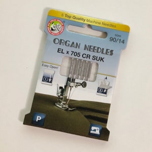 Op de afbeelding: Een verpakking met 5 Organ-naalden, maat 90/14, voor naaimachines. De naalden zijn zilverkleurig en worden geleverd in een doorzichtige plastic verpakking met een blauw-wit etiket. Het etiket vermeldt "Organ Needles EL x 705 CR SUK" en "Easy Open!"