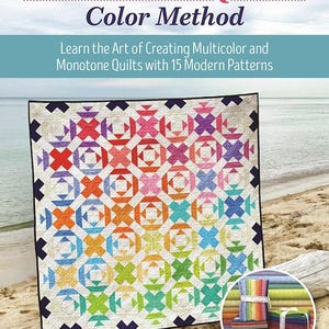 May include: A colorful quilt with a geometric pattern, displayed on a sandy beach. The quilt features a rainbow of colors and is the focal point of the image. The book cover reads "Rainbow Quilt Color Method".