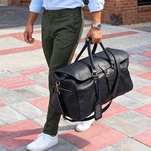 Full Grain Leather Duffle Bag held by a traveller using the grab handles.