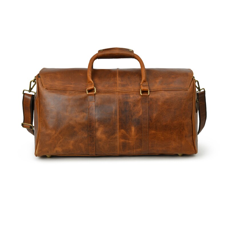May include: A brown leather duffel bag with a top handle and a shoulder strap. The bag has a distressed look and is made of high-quality leather.