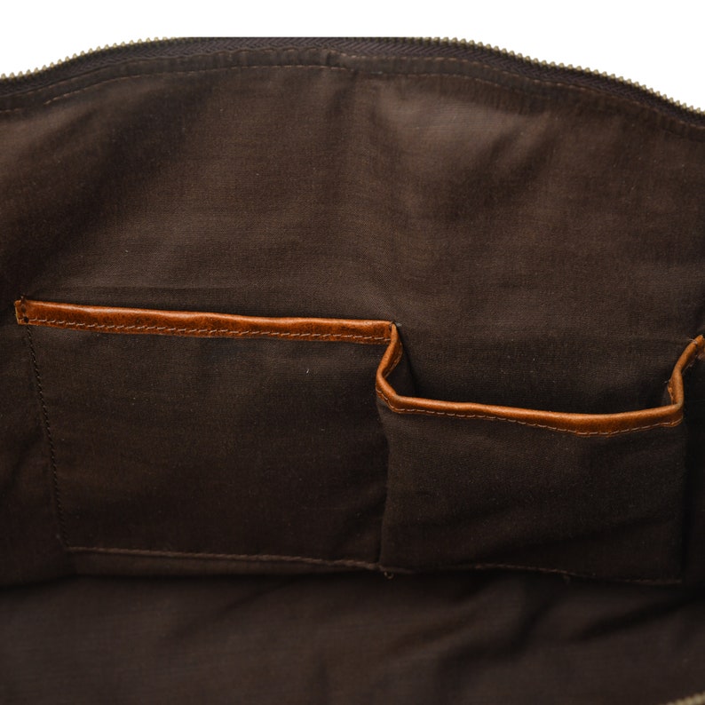 May include: The inside of a brown leather bag with two brown leather pockets. The bag is lined with a brown fabric.