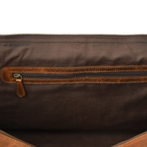 May include: The inside of a brown leather duffel bag with a zippered pocket. The bag is lined with brown fabric.