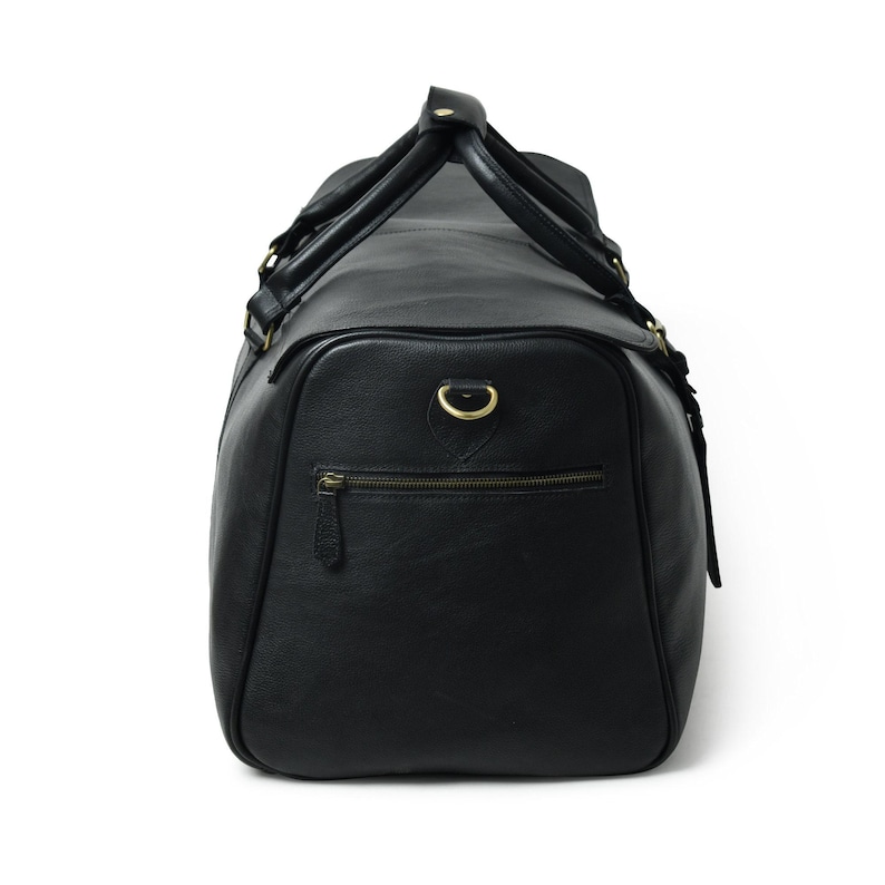 Side view of a black leather duffle bag with a zippered exterior pocket, brass hardware, and top handles buckled together.