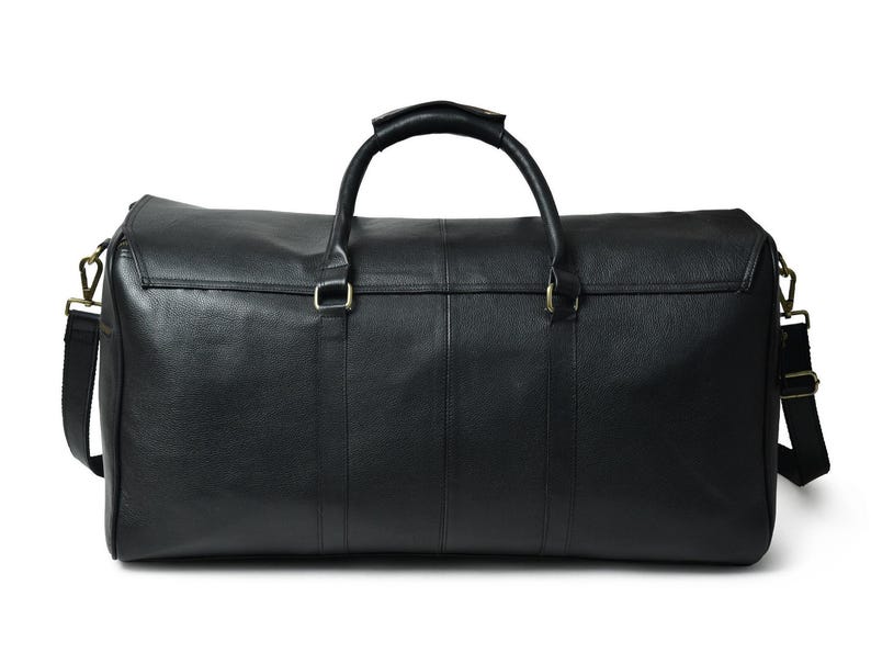 Front view of a black leather duffle bag resting on a white background with two top carrying handles and a detachable shoulder strap.