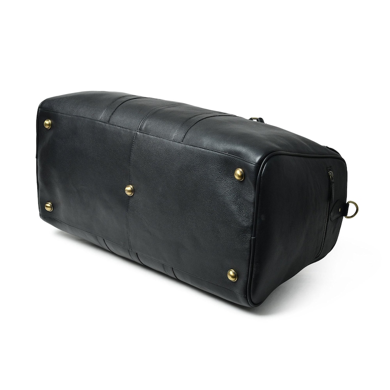 Bottom view of the black leather duffle bag featuring five brass protective feet studs.