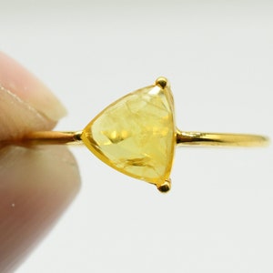 May include: A gold ring with a triangular yellow gemstone.