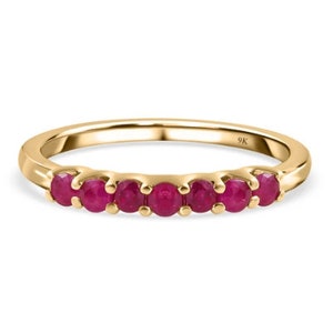 May include: A gold band ring with six small round ruby gemstones set in a row. The ring is marked "9K" on the inside.