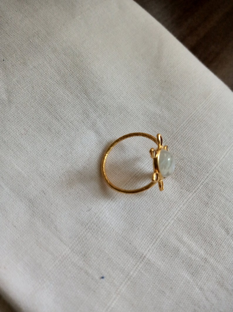 K&ouml;nnte beinhalten: Ein goldener Ring mit einem wei&szlig;en Edelstein, der in einem Schildkr&ouml;ten-Design gefasst ist.
