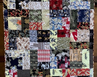 May include: A patchwork quilt with a variety of colorful fabrics featuring tropical patterns, geometric designs, and floral motifs. The quilt is made up of squares and rectangles of different sizes and colors, creating a visually interesting and textured surface.