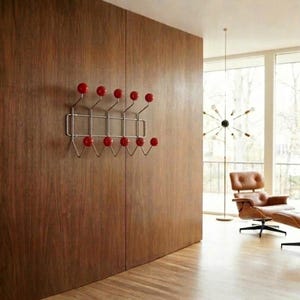 Puede incluir: Un perchero de estilo moderno de mediados de siglo con marco cromado y ganchos rojos en forma de bola. Montado en una pared de madera, muestra una mezcla de funcionalidad y diseño retro. Los ganchos están espaciados uniformemente, ofreciendo una solución de almacenamiento elegante.