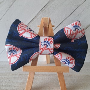 May include: A navy blue bow tie with a white baseball and the words "New York Yankees" printed on it.