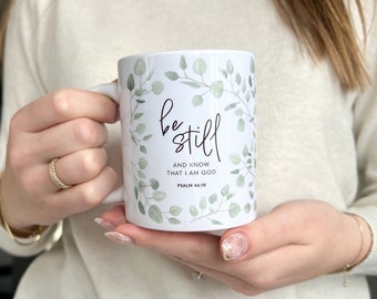May include: White ceramic mug with a green leafy design and the text "be still and know that I am God Psalm 46:10".