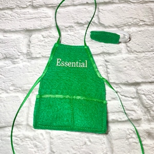May include: Green felt apron with a pocket and adjustable ties. The apron has the word "Essential" embroidered on the front in white thread.