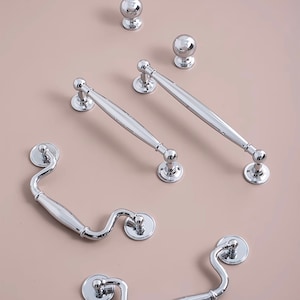May include: A set of five polished chrome cabinet hardware pieces, including two drawer pulls, two cup pulls, and one knob.