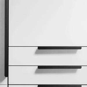 May include: Three white drawers with black rectangular handles. The drawers are part of a white cabinet.